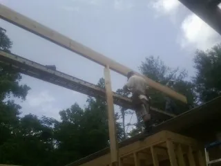 Carpenter setting a ridge beam over a new addition frame — Ice Dam Removal by Roofing Brothers in Dunbar