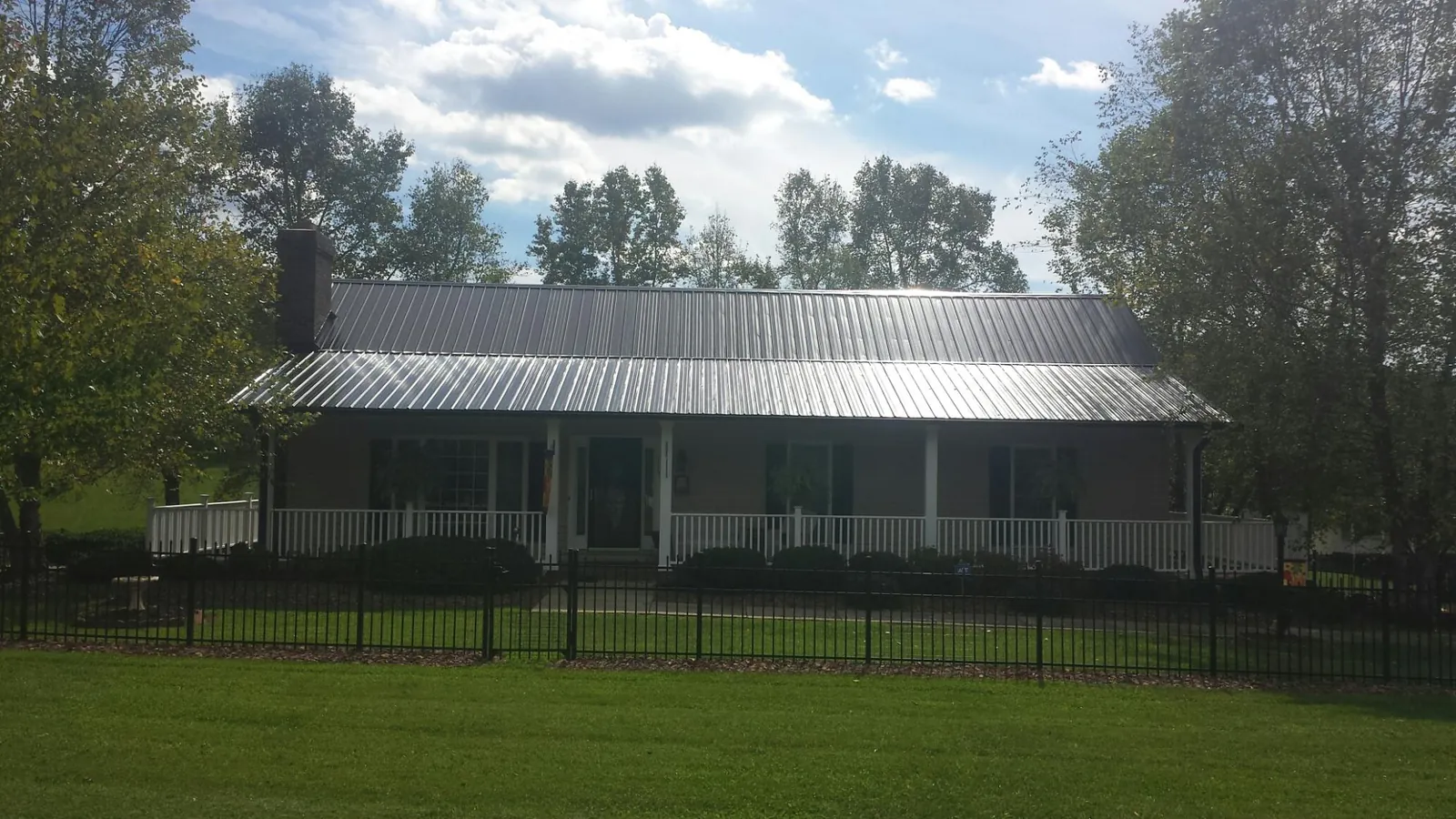 Gray metal roof on a brick ranch with a full width front porch — Gutter Guard Installation work by our crew in Dunbar
