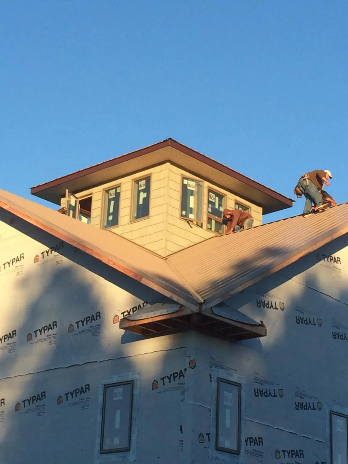 Roofers working around a rooftop cupola on a new metal roof at sunset — Roof Waterproofing in Dunbar by Roofing Brothers